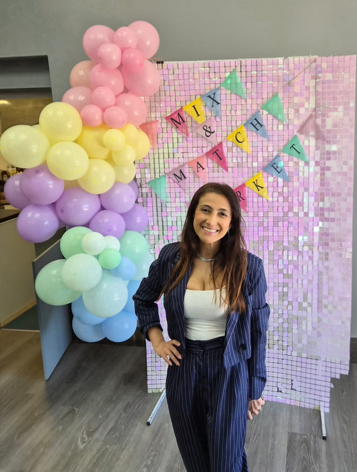 Marileia Borges, founder of Mix & Match Market, in front of the market's pastel balloon backdrop
